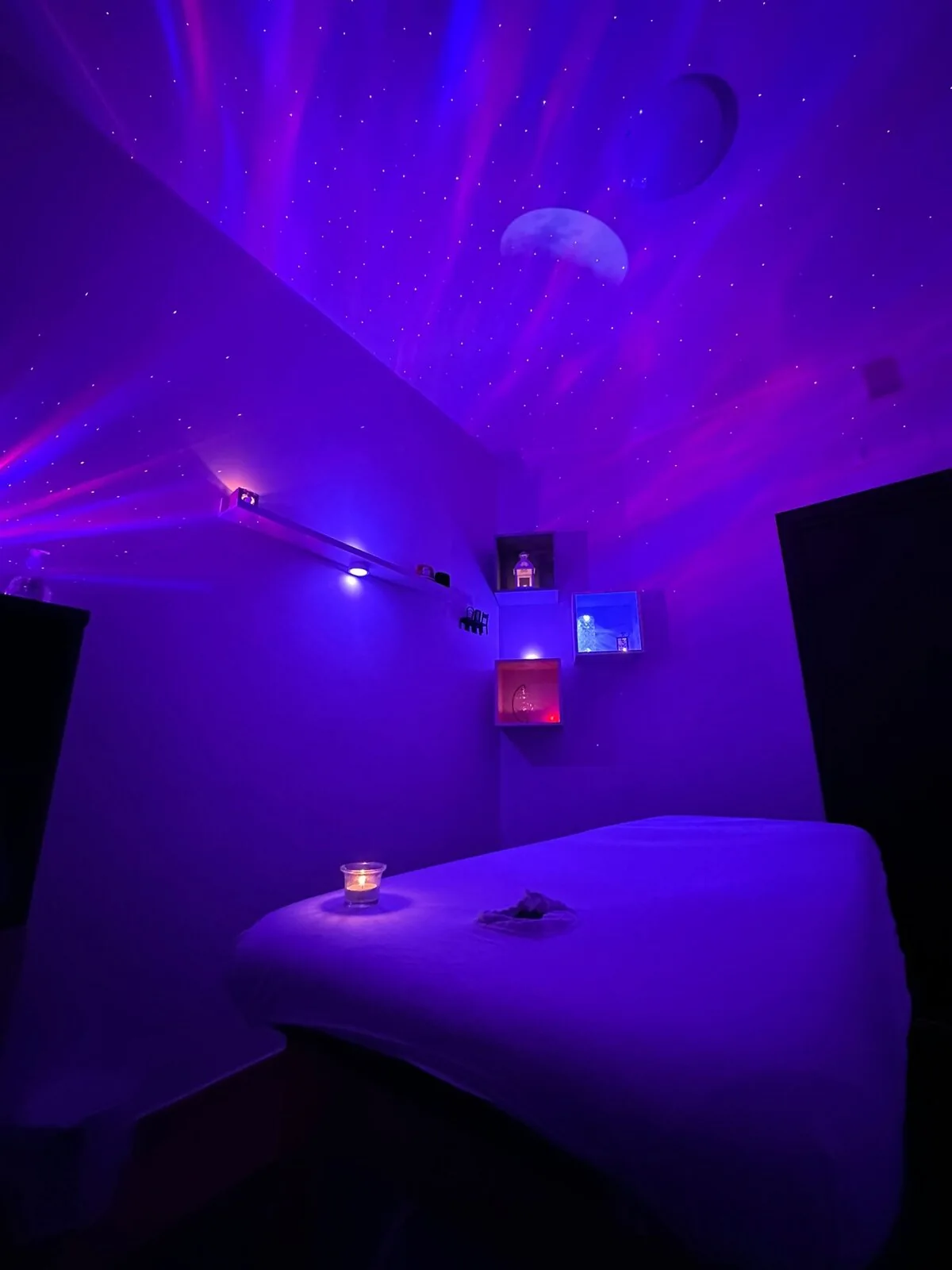 Un’altra vista dello spazio dedicato ai massaggi con lettino e luci soffuse viola